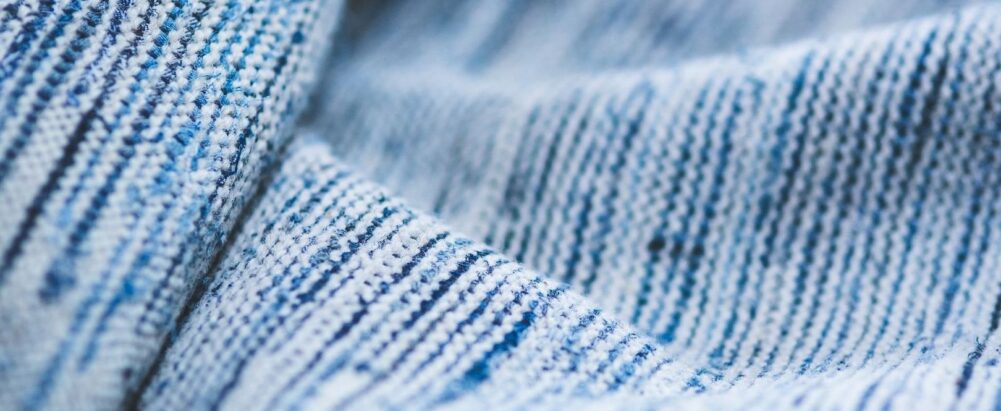 Close-up van zacht ogende blauw-witte textielstof met fijne weefstructuur