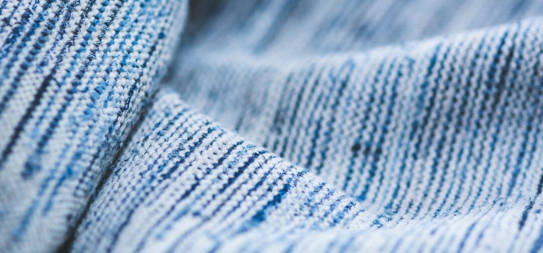Close-up van zacht ogende blauw-witte textielstof met fijne weefstructuur