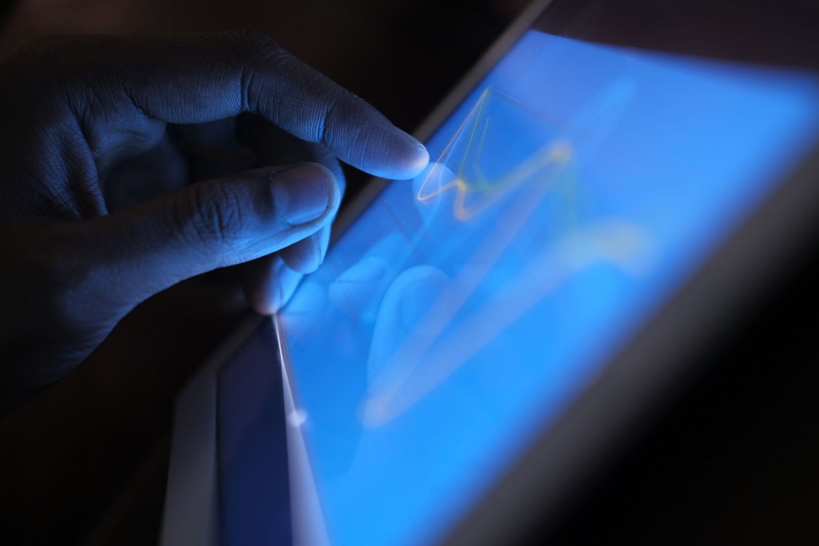 Hand die op een helderblauw tabletscherm tikt